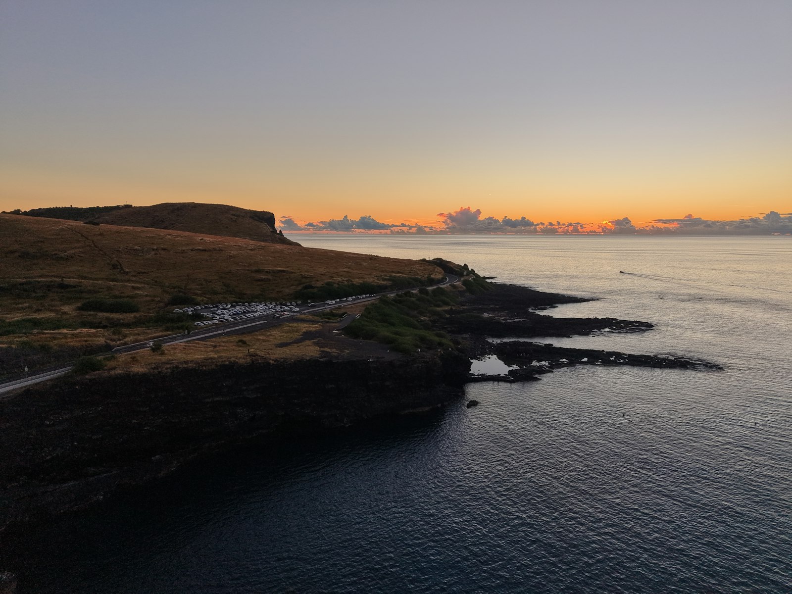A winding coastal road tracing a dramatic shoreline at sunrise
