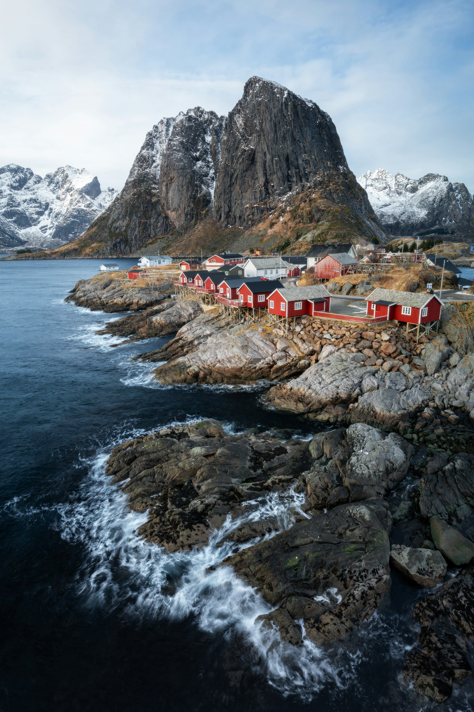 Red fishing cabins below steep peaks in the Lofoten islands, Norway
