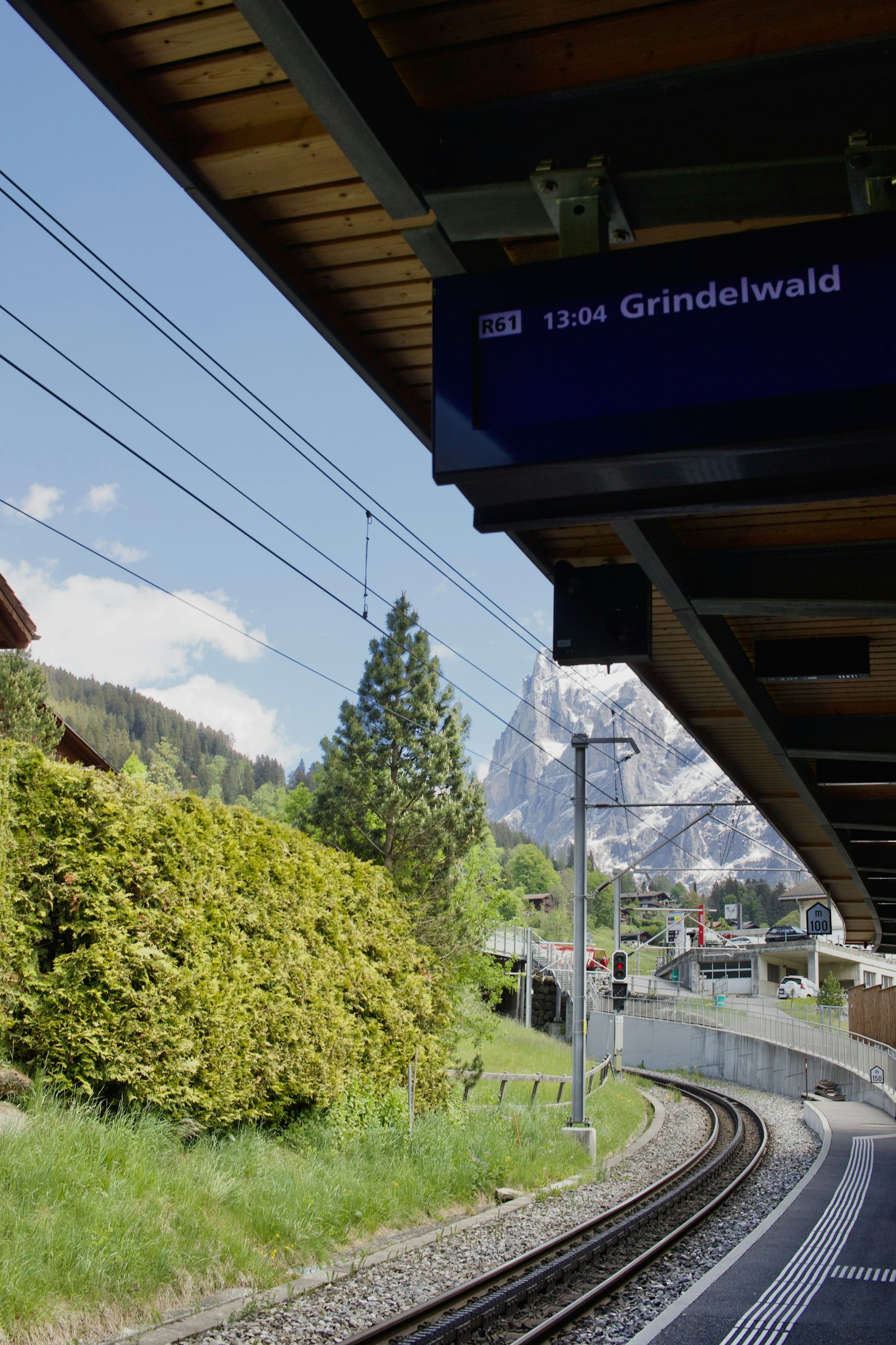 A traveller checking an itinerary on a phone beside a mountain railway platform